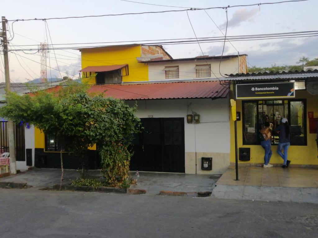 una mujer parada fuera de un edificio blanco y amarillo en Casa de relajación low cost, en La Dorada