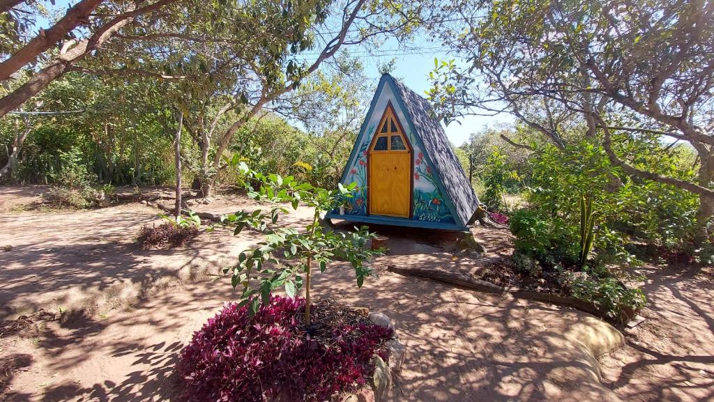 mały niebieski dom z żółtymi drzwiami w ogrodzie w obiekcie Camping Permacultural Filhos da Floresta w mieście Vale do Capao