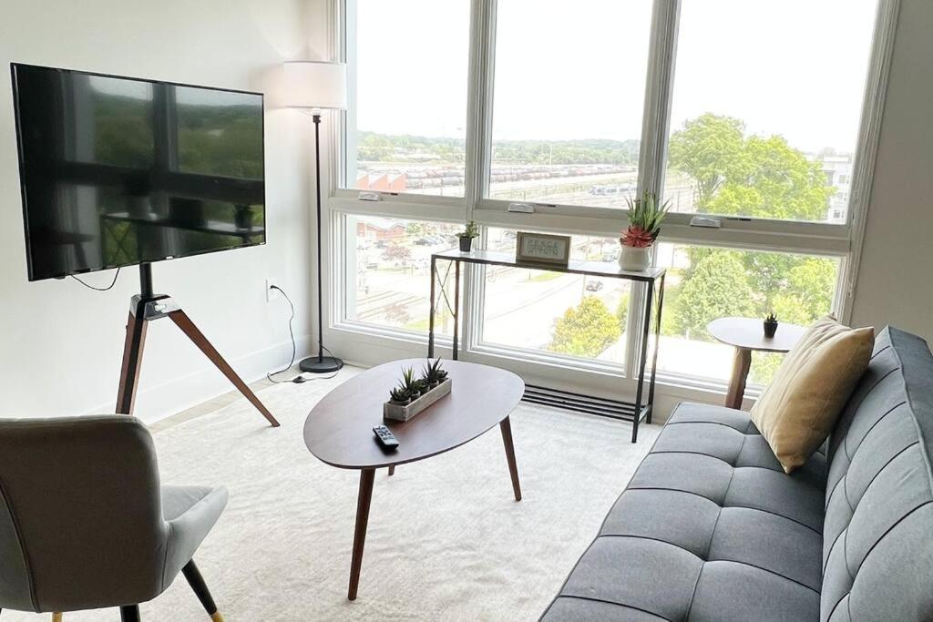 a living room with a couch and a table and a tv at Modern Queen Bed & Twin Futon Studio with WiFi, Kitchen, Washer, and Dryer in Charlotte