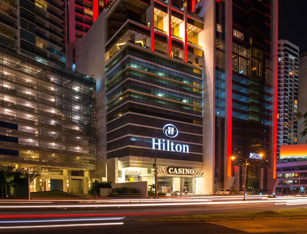 Um edifício alto com um sinal de Hilton à noite. em Hilton Panama em Cidade do Panamá