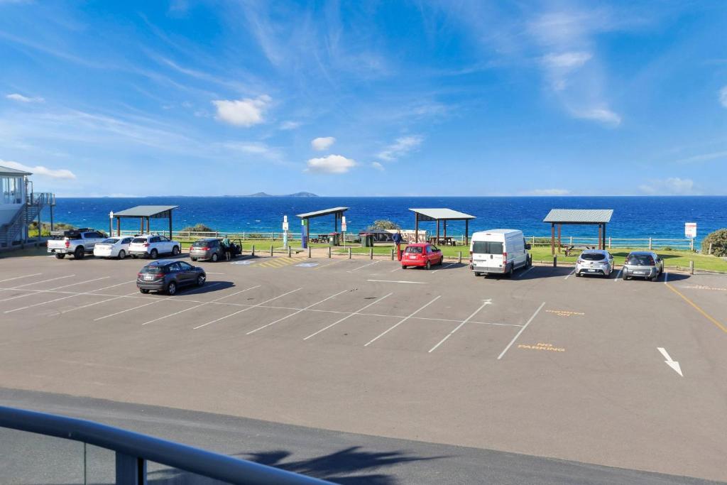 a parking lot with cars parked in front of the ocean at Nautilus 5 in Hawks Nest