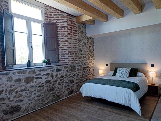 a bedroom with a bed and a brick wall at El Esquileo in Buitrago del Lozoya