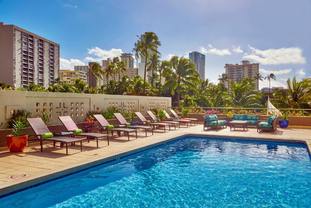 a pool with chaise lounge chairs and a bunch at DoubleTree by Hilton Alana - Waikiki Beach in Honolulu