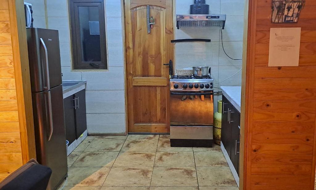 een kleine keuken met een fornuis en een koelkast bij GLAMPING CABAÑA HOLMBERG in Coihaique