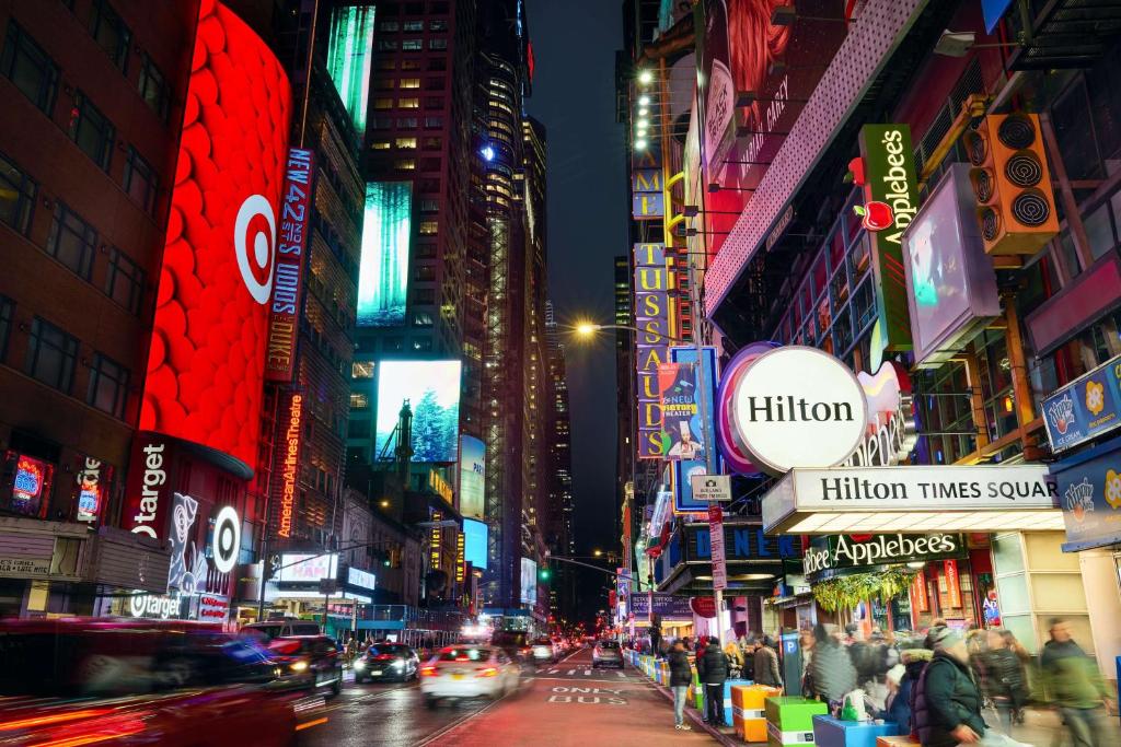 una concurrida calle de noche con coches y edificios en Hilton New York Times Square en Nueva York