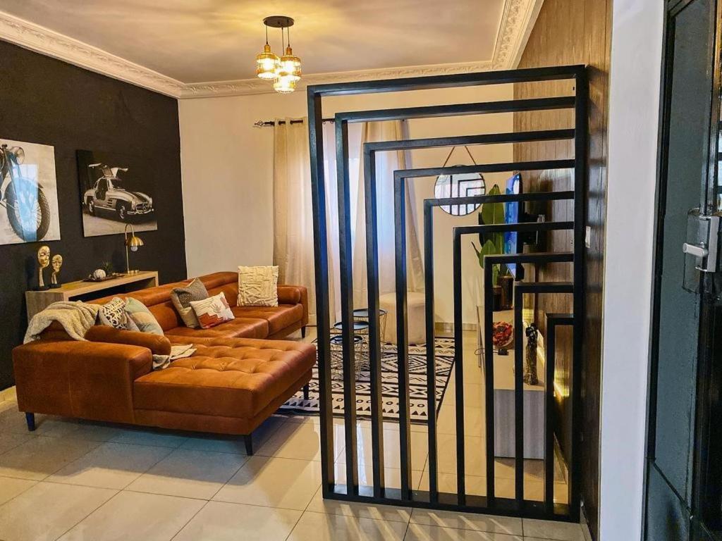 un soggiorno con divano e porta a vetri di Roswell Luxury Properties Yaoundé - Quartier FOUDA a Yaoundé