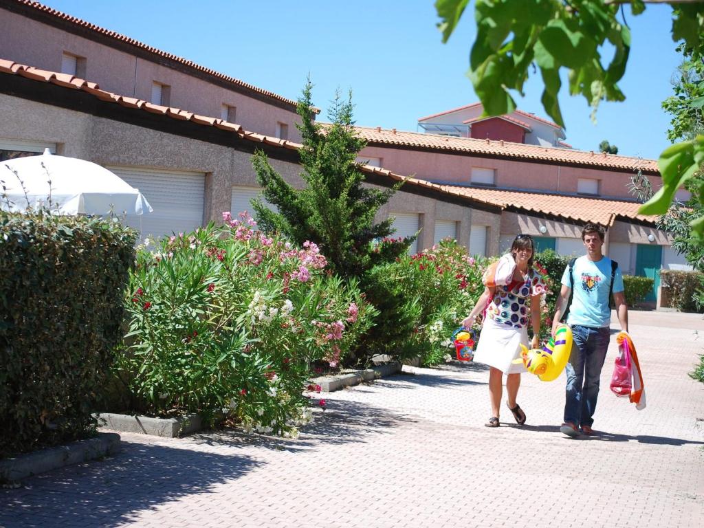 un homme et une femme marchant sur un trottoir dans l'établissement Apartment in Jardins de Neptune with Terrace, à Saint Cyprien Plage