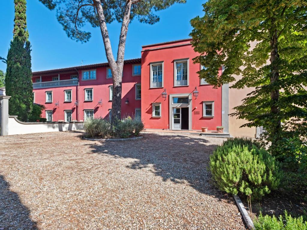 un edificio rojo con árboles delante de él en Modern Holiday Home in Rignano sull'Arno with Swimming Pool, en Rignano sullʼArno