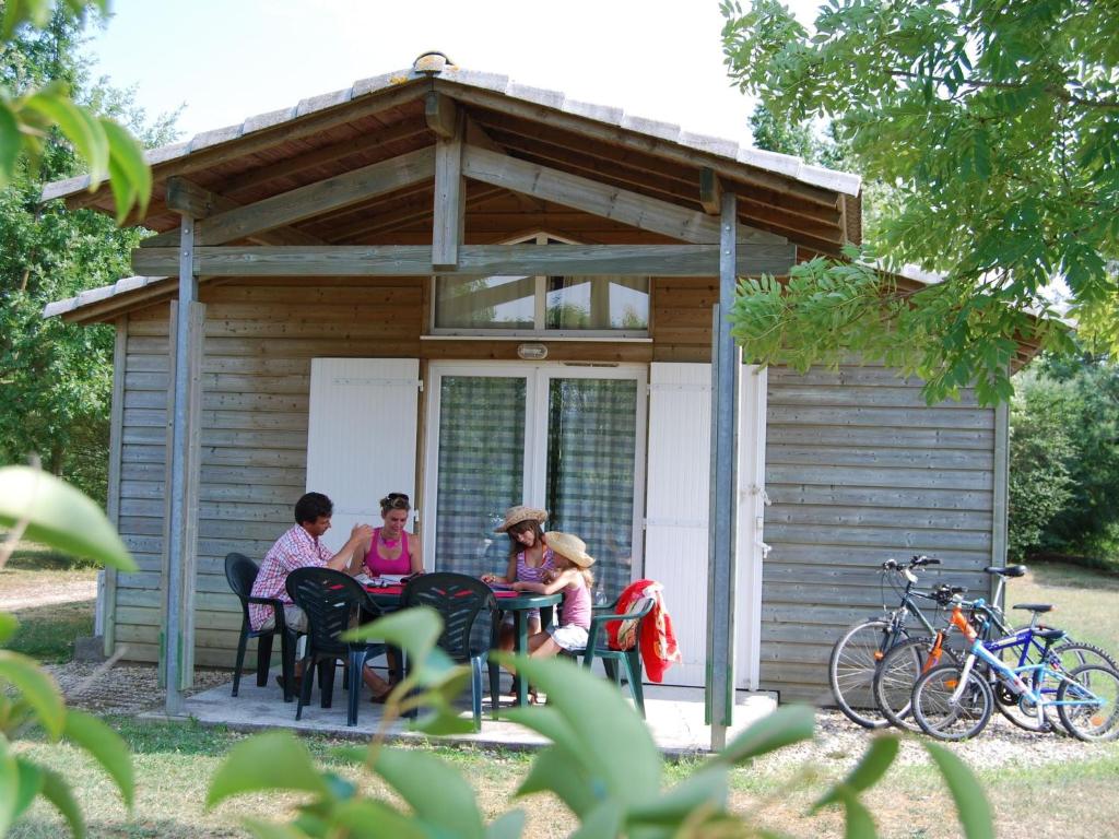 tres mujeres sentadas en una mesa frente a una cabaña en Detached chalet with dishwasher, on the banks of the Lot, en Castelmoron-sur-Lot