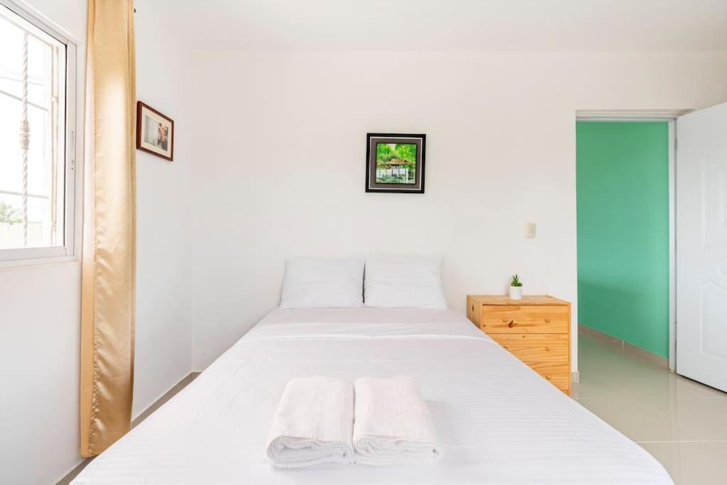 a bedroom with a white bed with two towels on it at SDQ airport & Samana bus near Bamboo in Santo Domingo