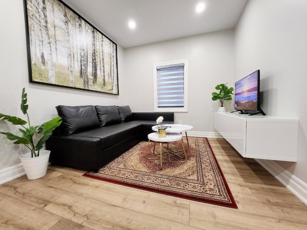 a living room with a black couch and a table at The Cozy Cove Modern King-Bedroom Full Apartment in St. Catharines