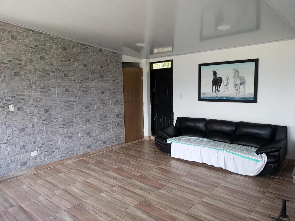 una sala de estar con un sofá de cuero negro en una habitación en habitación en Villa Tina, en Santa Rosa de Cabal