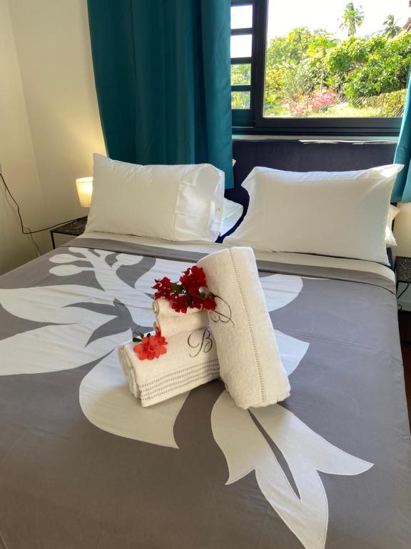 a hotel room with two beds with towels and flowers at Manaeva L6 in Faaa
