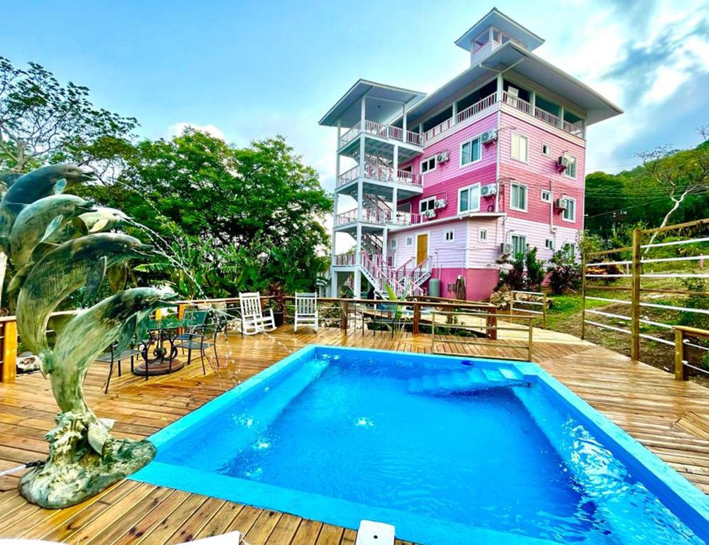 a swimming pool in front of a pink building at Hummingbird in Utila