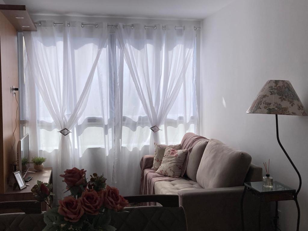 a living room with a couch in front of a window at Melhor Ap Poços de Caldas in Poços de Caldas