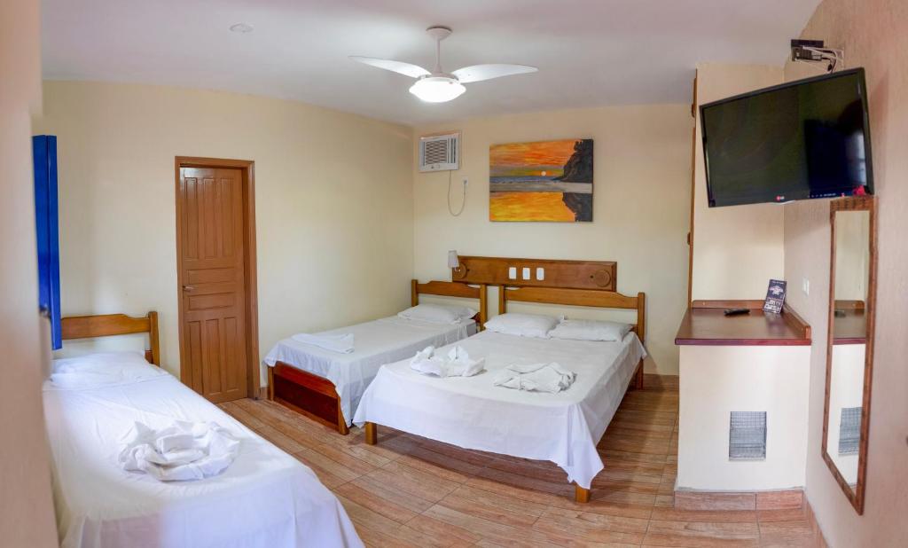 a room with two beds and a flat screen tv at Hotel Lazaro Ubatuba Ltda in Ubatuba