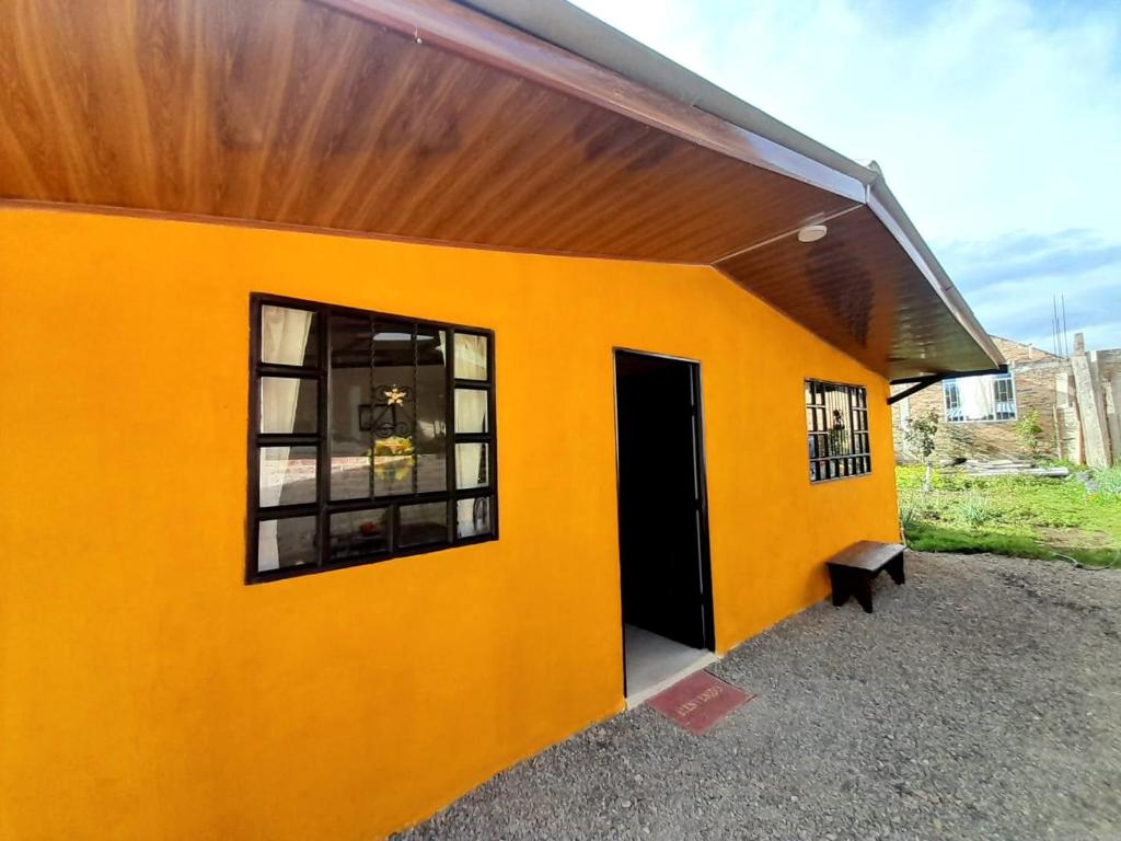 a yellow building with a black door and a bench at CASA TURISTICA SAN JUAN DE OTTI in Monguí