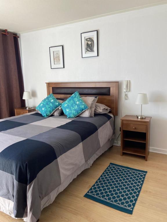 - une chambre avec un grand lit et des oreillers bleus dans l'établissement Agradable departamento, frente a la Quinta Vergara, à Viña del Mar
