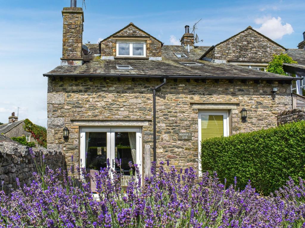 una casa de piedra con flores púrpuras delante de ella en Hoopers End en Sedgwick