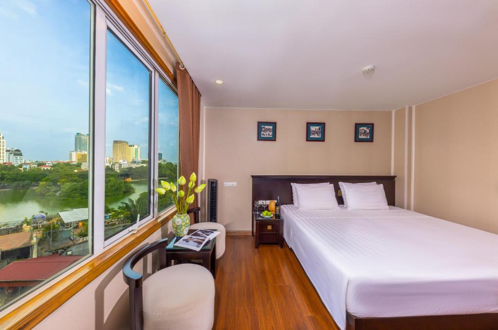 a bedroom with a bed and a large window at Centre Point Hanoi Hotel in Hanoi