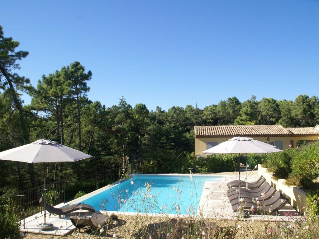 - une piscine avec deux parasols et des chaises dans l'établissement Gorgeous Apartment in Montauroux with Pool, à Montauroux