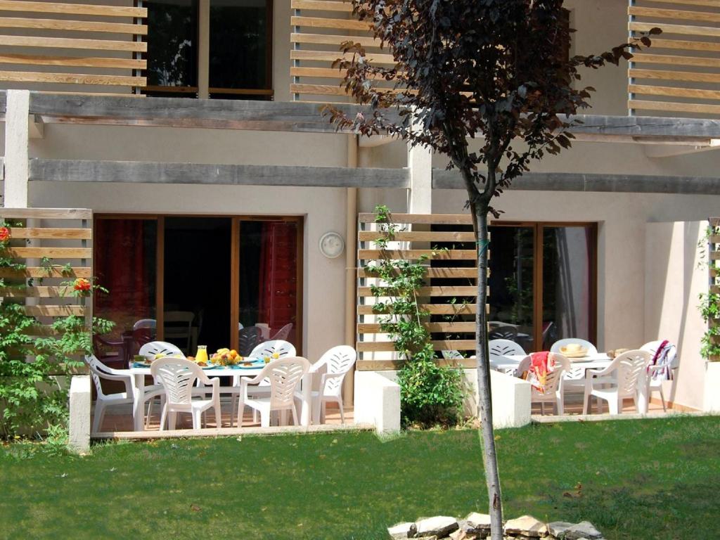 d'une terrasse avec des chaises blanches et une table dans la cour. dans l'établissement Apartment in France with Spacious Terrace, à Barjac