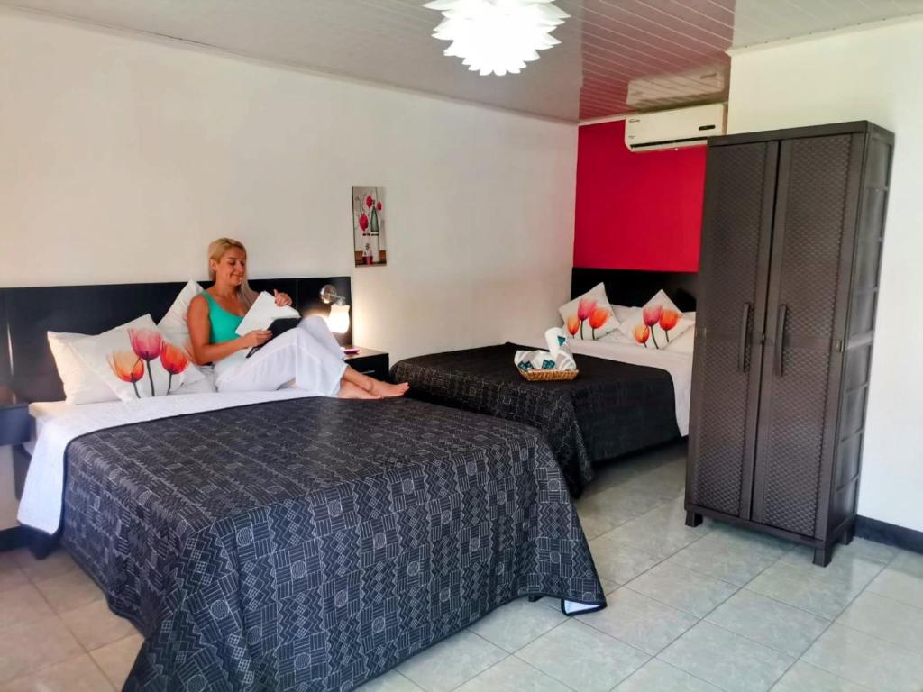 a woman sitting on a bed in a hotel room at Roca Mar ROCAWELCH Puerto Viejo in Puerto Viejo