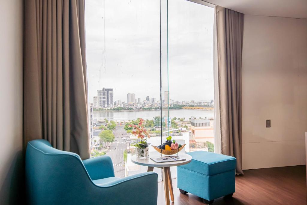 a room with a table and chairs and a large window at Gold Hotel Da Nang by Haviland in Danang