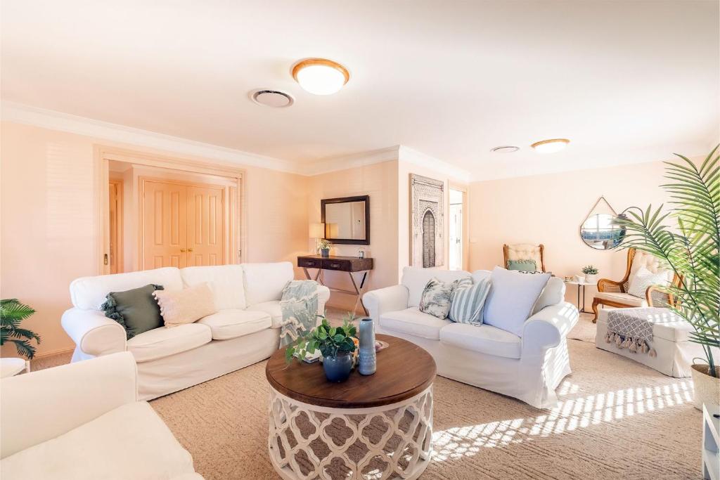 een woonkamer met twee witte banken en een tafel bij White Sands, 14 Whitesands Road - Pet Friendly, Linen & Air Con in Fingal Bay