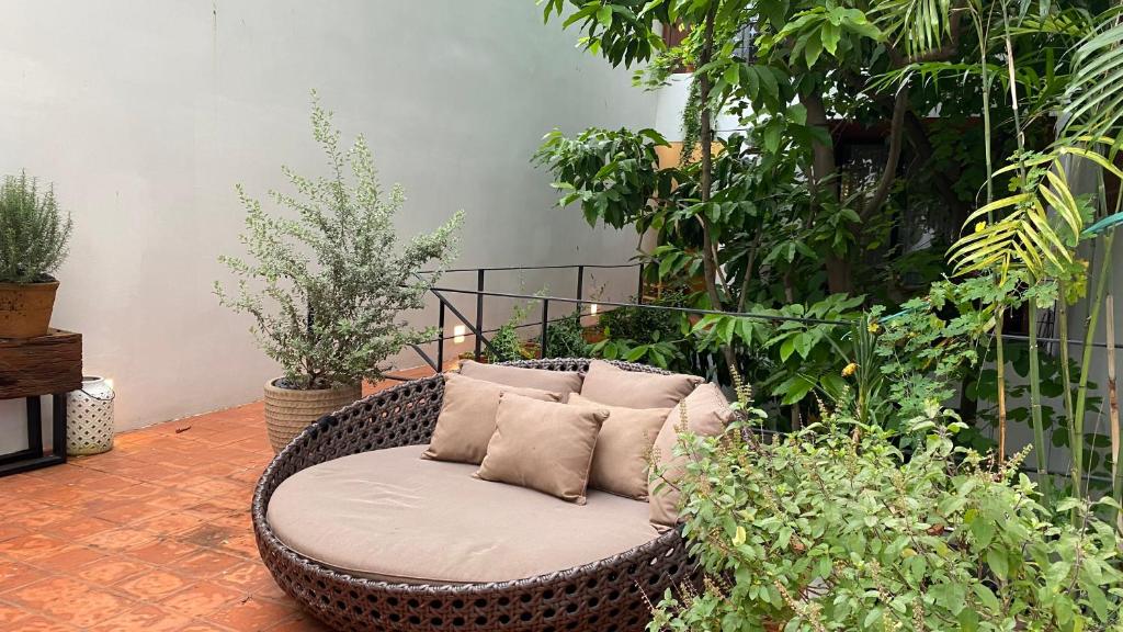 a wicker chair with pillows on a patio with plants at Notre Maison 8 Saigon close Landmark 81 building in Ho Chi Minh City