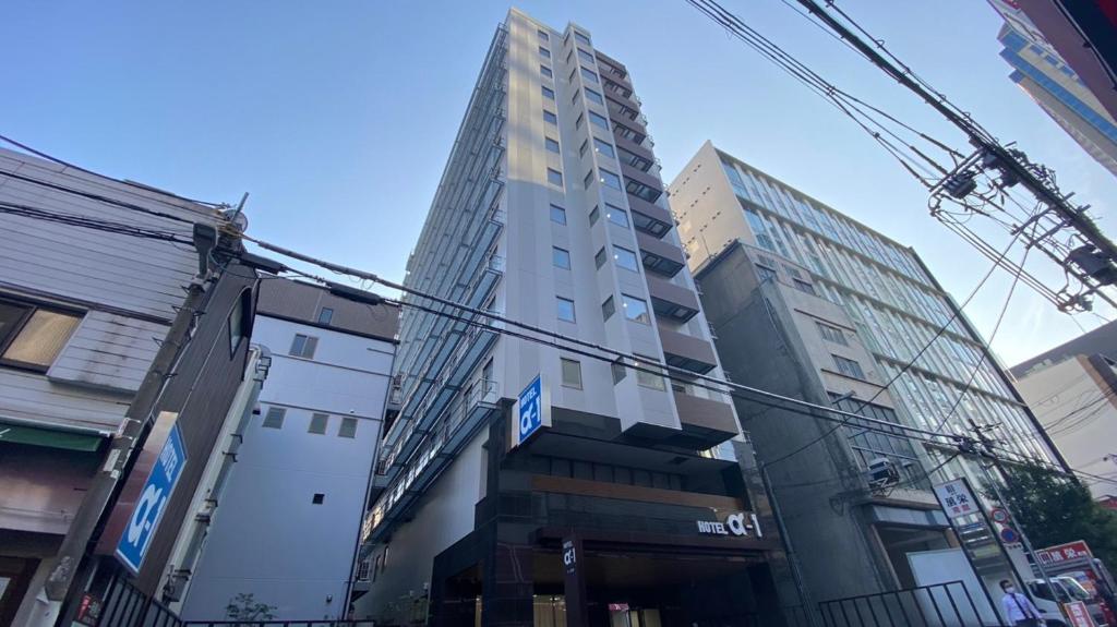 um edifício alto no meio de uma cidade em Hotel Alpha-One Kitashinsaibashi em Osaka