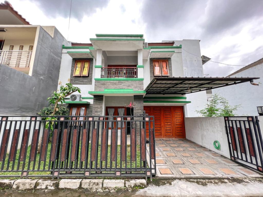 a house with an orange door and a fence at Homestay Simply Homy Jogja dekat Ambarukmo plaza in Yogyakarta