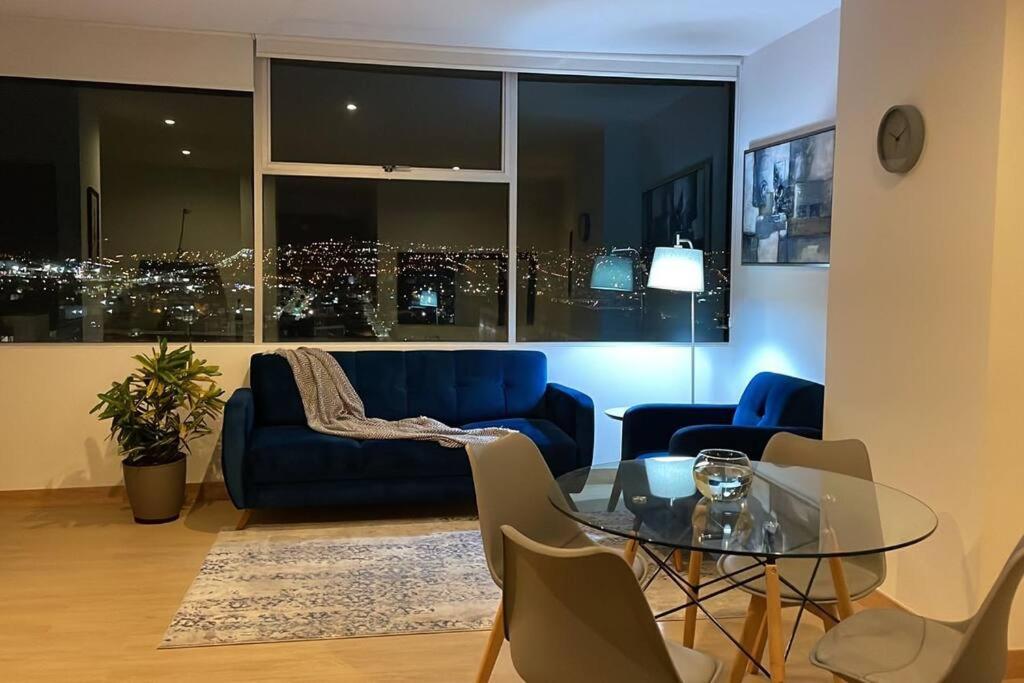 een woonkamer met een blauwe bank en een glazen tafel bij Lujosa Suite piso 19 La Carolina in Quito