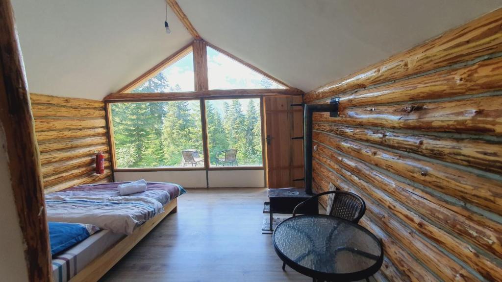 ein Schlafzimmer in einem Blockhaus mit einem Bett und einem Fenster in der Unterkunft Echoes of the mountains in Mestia