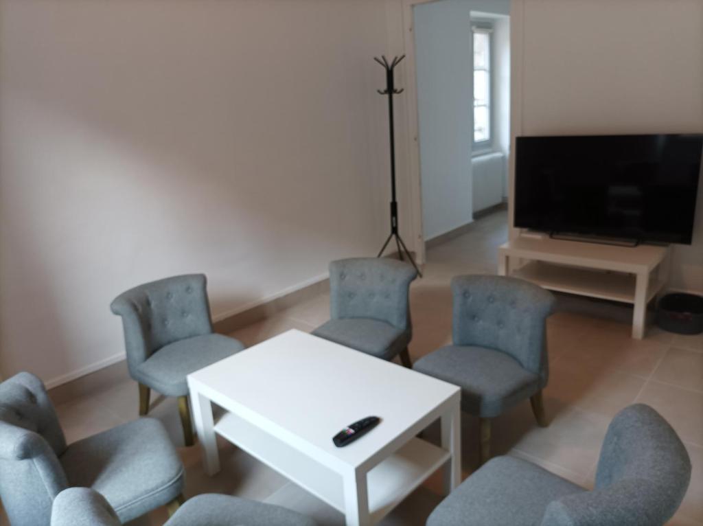 a living room with chairs and a table and a tv at O'Couvent - Appartement 441 - 3 chambres - 97 m2 - Quatrième étage in Salins-les-Bains