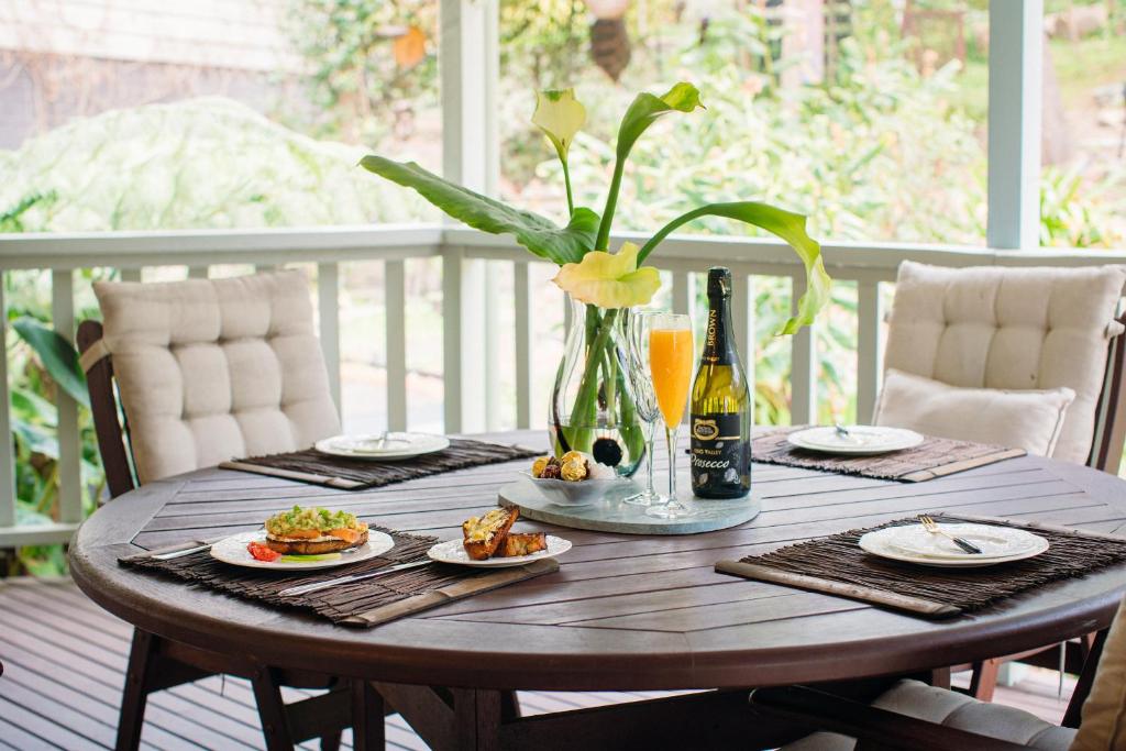una mesa de madera con platos de comida y un jarrón con flores en Snooty Fox Bed &Breakfast en Hazelbrook