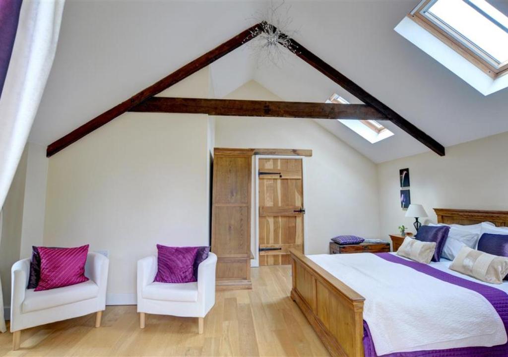 a bedroom with a large bed and two white chairs at Felin Fach in Pumpsaint