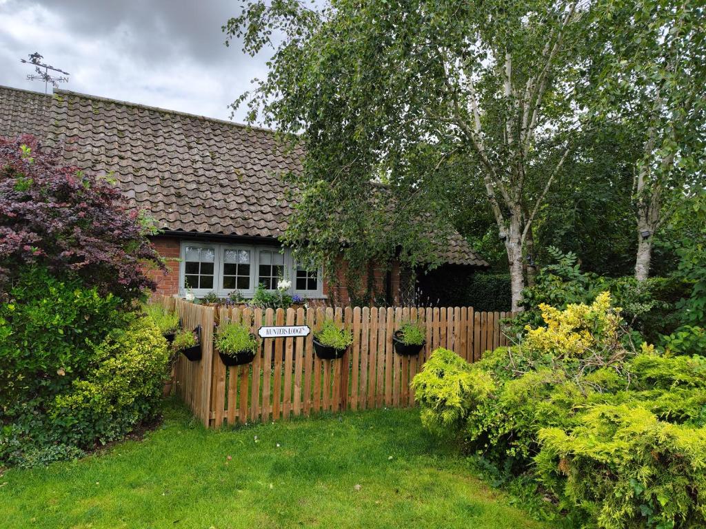 een houten hek in een tuin met potplanten bij Hunters Lodge in Norwich