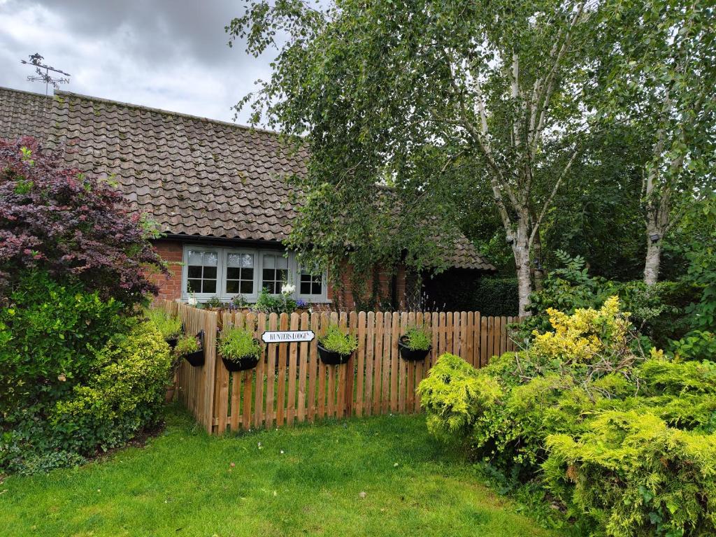 a wooden fence in a yard with potted plants at Hunters Lodge in Norwich