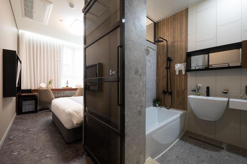 ソウルにあるHotel DMのバスルーム(バスタブ、シンク、ベッド付)