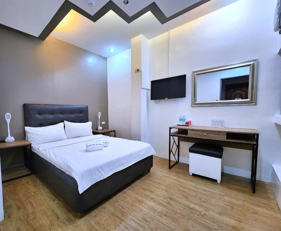 Dormitorio con cama, escritorio y TV en New Kong's Hotel, en Olóngapo