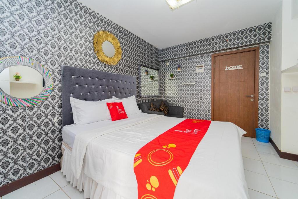 een slaapkamer met een bed met een rode deken erop bij RedLiving Apartemen Cinere Resort - Gold Room in Gandul
