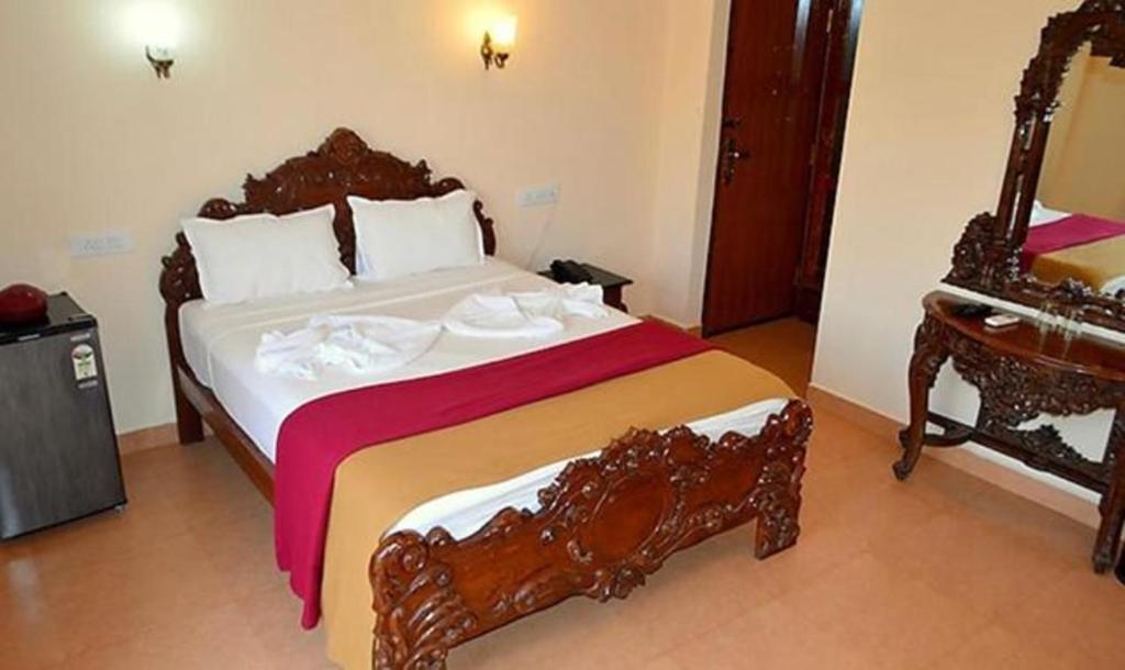 a bedroom with a large bed with a wooden frame at FabExpress VT Resort With Pool, Calangute Beach in Calangute