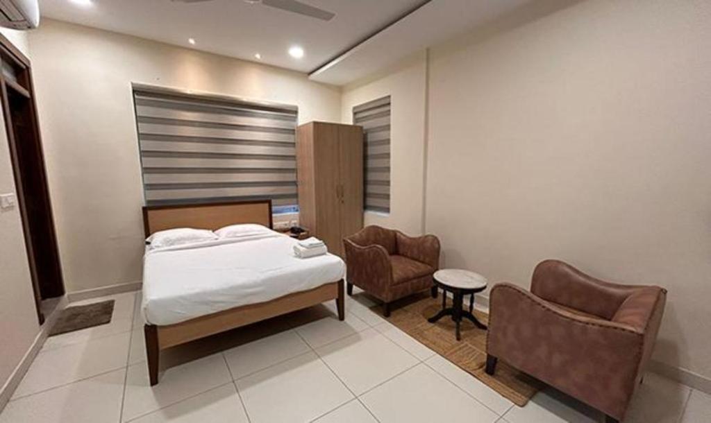 a bedroom with a bed and a chair at FabHotel Prime AM Suites Near Yashoda Hospital in Hyderabad