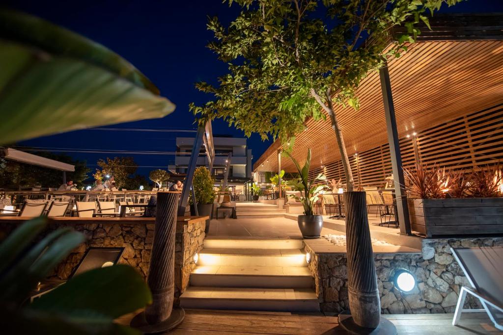 a patio with tables and trees at night at Ostria Sea Side Hotel in Hanioti
