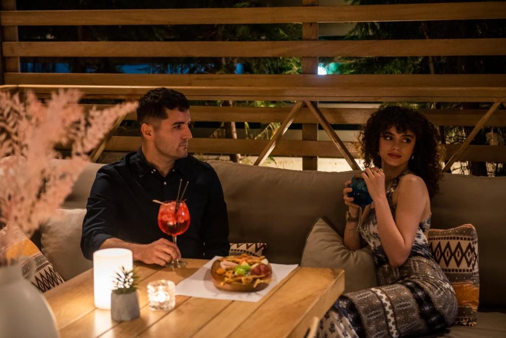 a man and woman sitting at a table with a plate of food at Ostria Sea Side Hotel in Hanioti