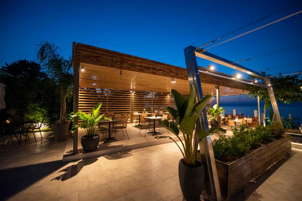 a patio with tables and potted plants at night at Ostria Sea Side Hotel in Hanioti