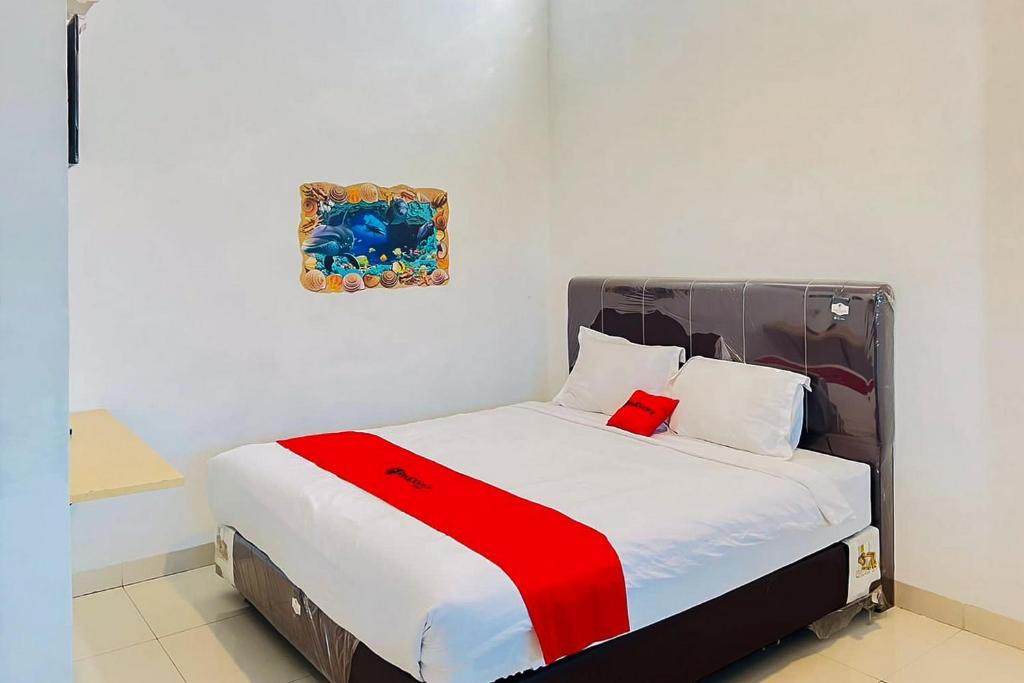 ein Bett mit einer roten und weißen Decke drauf in der Unterkunft RedDoorz At Damai Guest House Kabanjahe in Kabanjahe