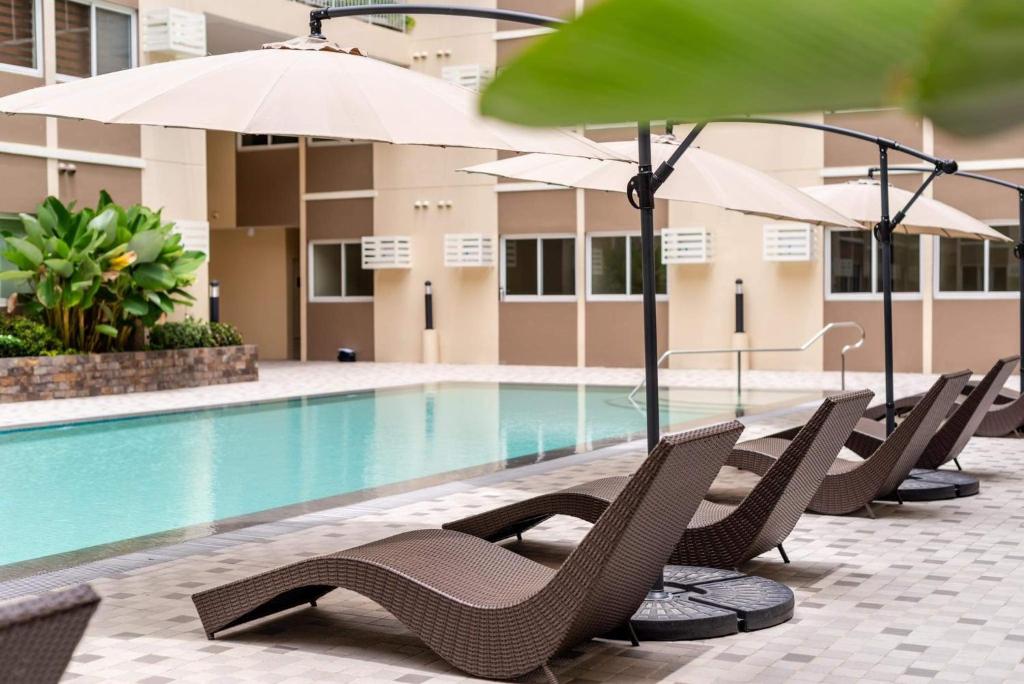 a pool with chairs and umbrellas next to a building at Stanford Suites 3 in Silang