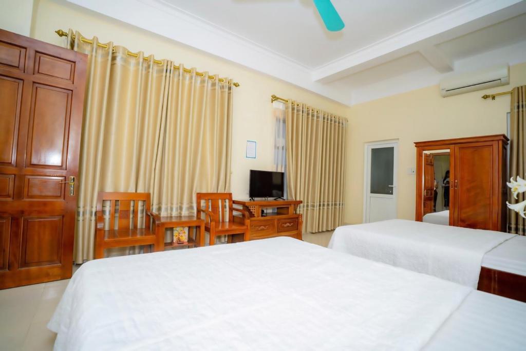 a bedroom with two beds and a table and chairs at Lai Dinh Hotel in Sầm Sơn